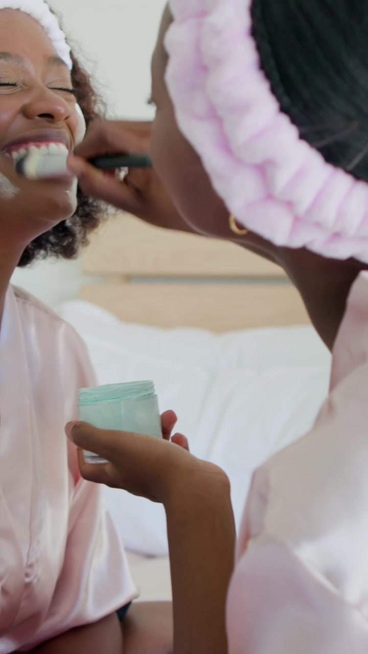 Vertical video: Dipping child in robe with mint jar brushing mom's face on bed, bonding, copy space