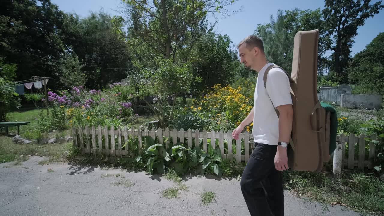 숲 근처의 거리에서 기타를 들고 는 젊은 남자