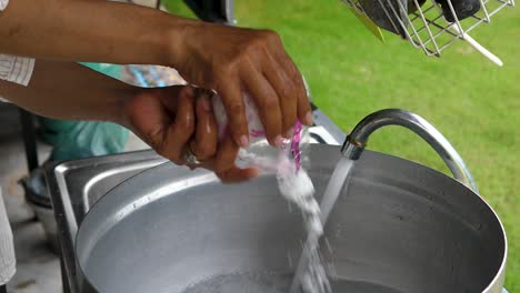 motion shot woman adding salt into water in a saucepan on outdoor kitchen