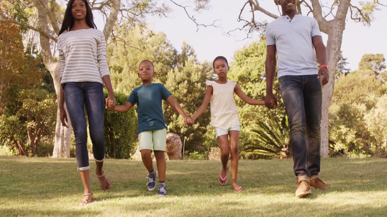 vista de ángulo bajo de una familia feliz tomados de la mano y caminando