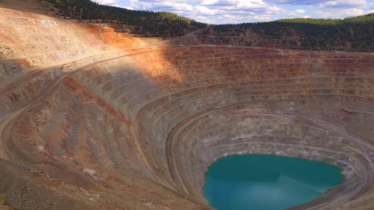 Flyfoto av en stor dagbruddsgruve med en turkis innsjø