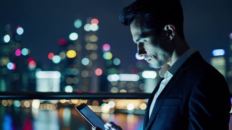 businessman using tablet/smartphone at night in city