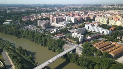 drone aéreo moviéndose hacia atrás disparado sobre una vieja estructura de hierro, gazómetro al lado de un río que fluye en el distrito de ostiense, roma, italia durante la noche