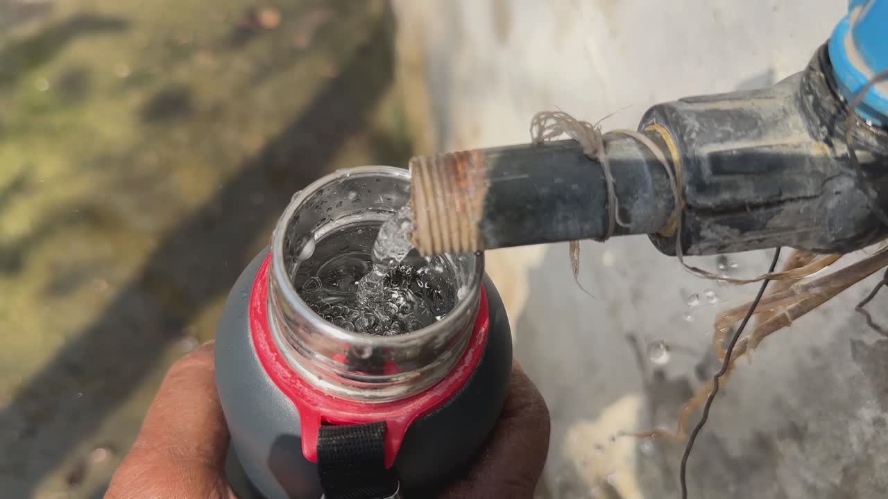 closeup of filling a water bottle from the open tap