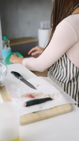 woman preparing fish in kitchen