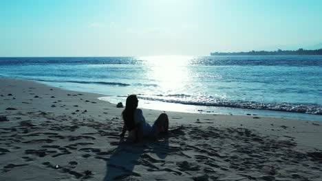 beautiful young lady relaxing on holiday at a tropical beach getaway, with the bright sun glistening in the water