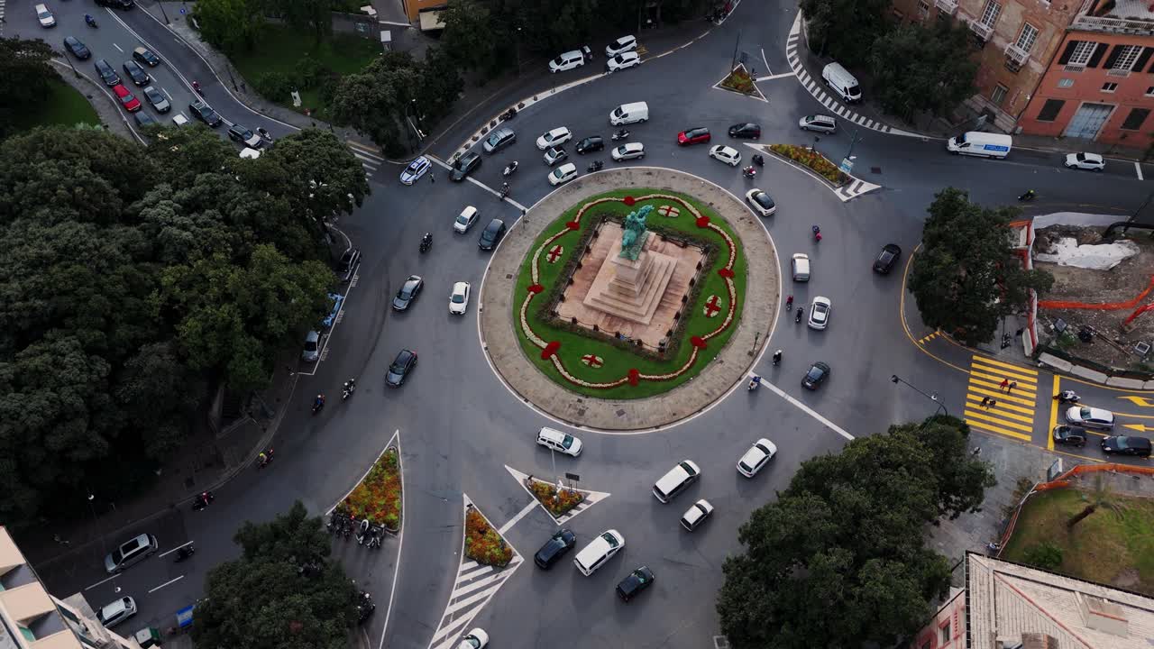 Traffic moving around a roundabout in the heart of genoa, italy at sunset, aerial view