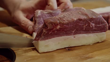 cortar el bistec con un cuchillo de cocina de acero contra el nervio en una tabla cortada de madera