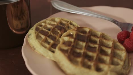 Pouring-a-sweet-sauce-in-a-plated-baked-pastry-with-whole-raspberries-on-the-side-and-a-fork---close-up