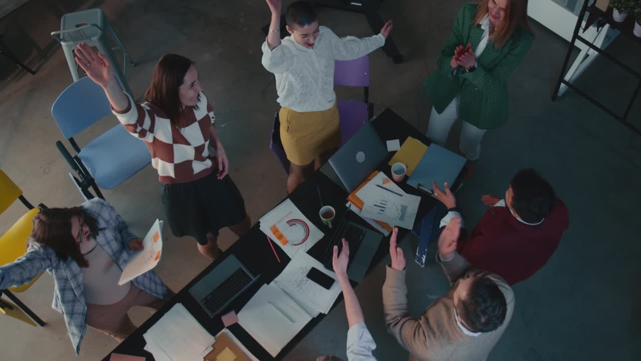 행복한 사업가 그룹이 팀워크의 성공을 축하합니다. 사무실에서 손을 잡고, 슬로우 모션으로 하이 파이브를 합니다.