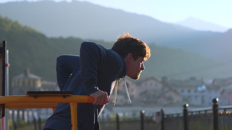 Man doing pull-ups in a park at sunrise