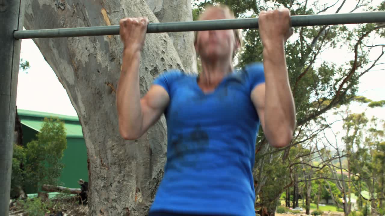 mujer en forma haciendo ejercicio en la barra durante una carrera de obstáculos