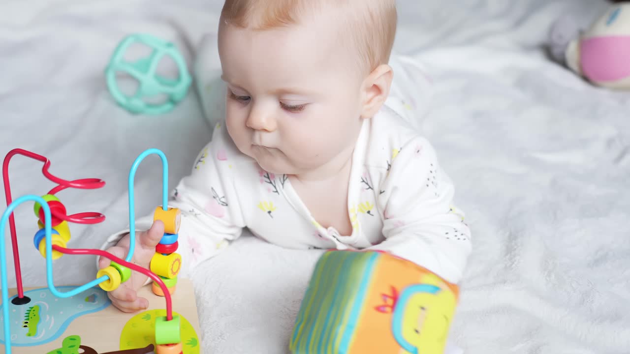 Baby Girl Laying On Her Stomach On Mat Playing Educational And Colorful Toys. - closeup shot