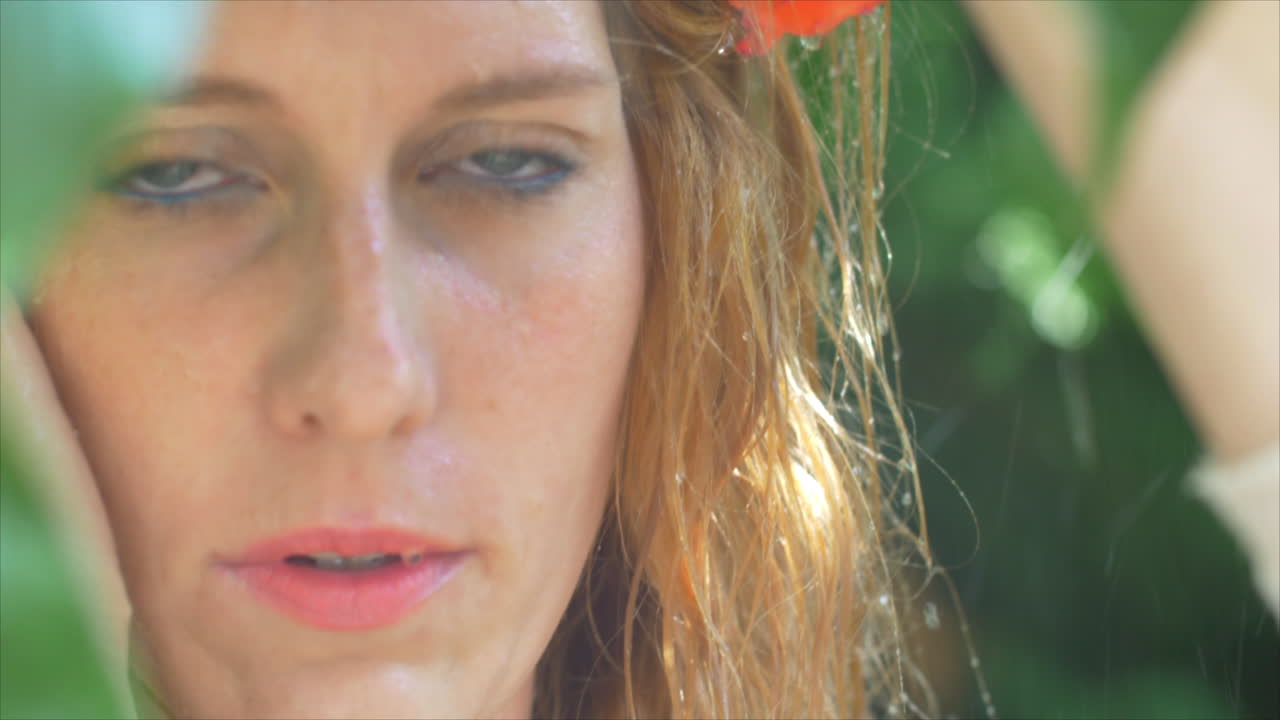 녹지로 둘러싸인 비에 서있는 파란 눈을 가진 젊은 여자