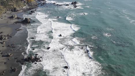 4K-Drohnenaufnahmen-Von-Wellen,-Die-Auf-Felsen-Und-Sandstrand-An-Der-Küste-Von-Brookings,-Oregon,-Krachen