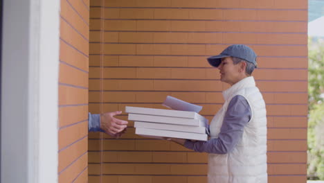 female courier in uniform delivering pizza to man at his home