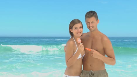 couple eating water ices on a beach