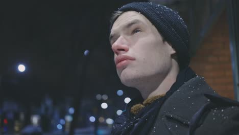 caucasian man standing outdoors at night with snowfall in winter