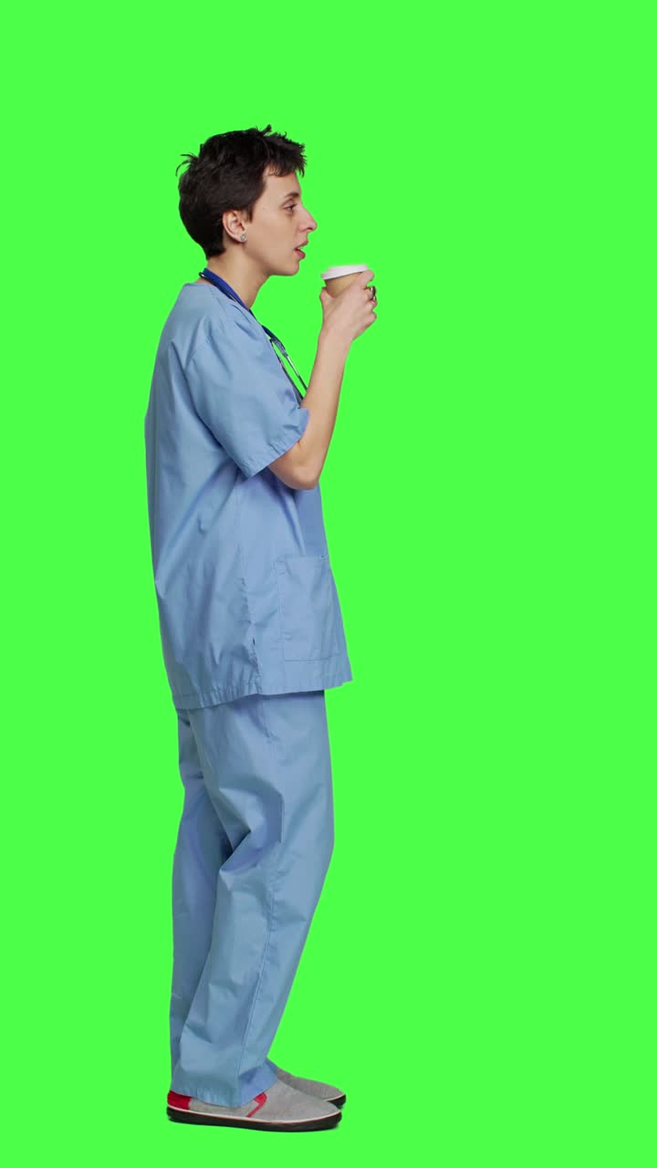 Profile Healthcare specialist enjoying hot coffee cup against greenscreen backdrop