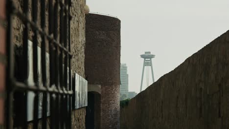 ancient stone walls with metal bars contrast with the ufo tower in bratislava