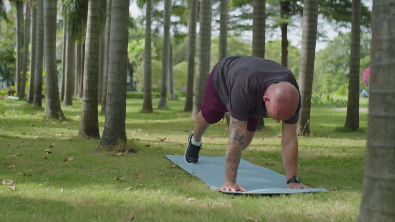 Man Doing Yoga on Exercise Mat in Park