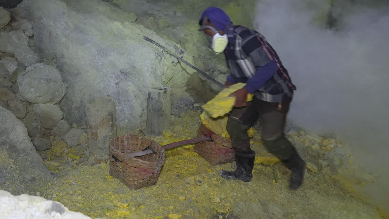 Miner working with sulfur pieces under toxic gas cloud in East Java