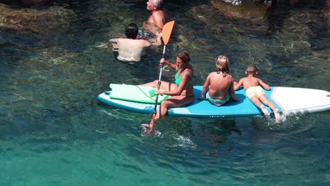 family enjoying paddle boarding in clear waters