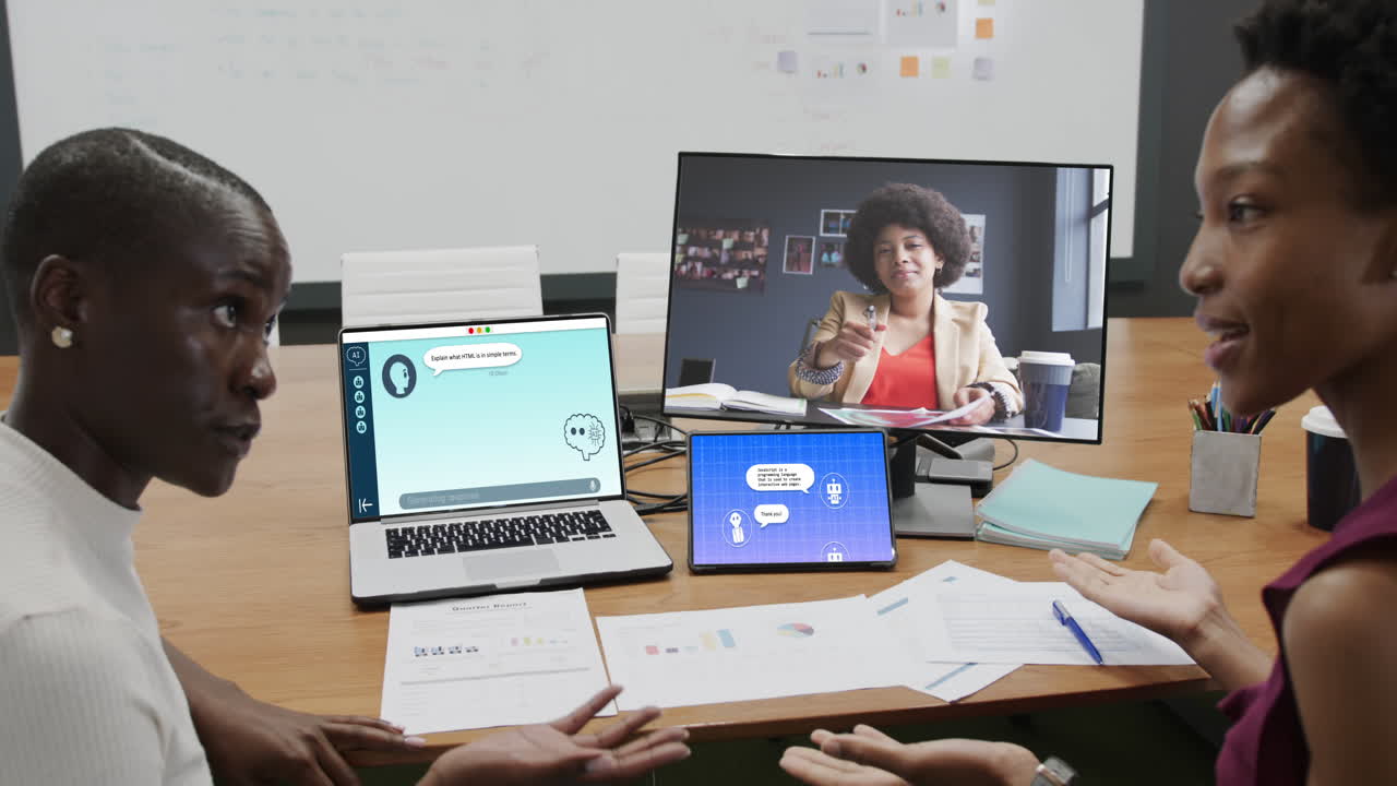 Diverse businesswomen in office using computers with video call and ai messaging on screens