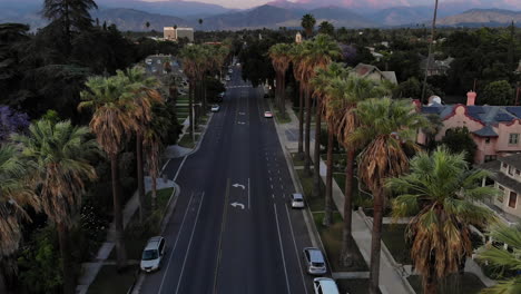 Vídeo-Nocturno-Con-Drones-De-Una-Calle-Principal-Bordeada-De-Palmeras-En-Redlands,-California