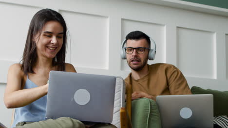 student talking with female mate sitting on sofa while looking at laptop 3