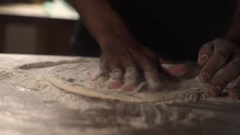 chef masculino de 4 k amasando masa de pizza casera en una mesa de madera