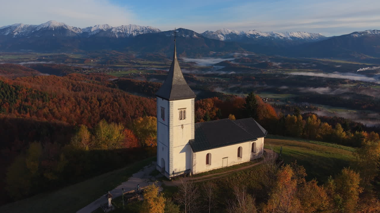 Aerial view of Saints Primus and Felician church in Jamnik with the Kamnik Savinja Alps background