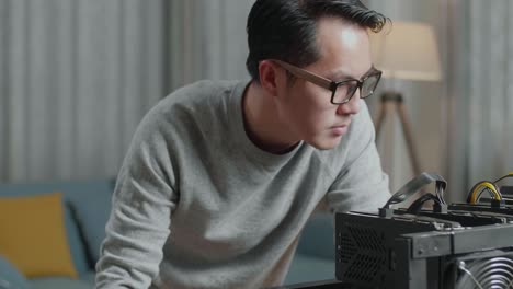 primer plano de un hombre asiático satisfecho con gafas mirando la plataforma de minería para la minería de criptomonedas mientras trabaja con una computadora portátil
