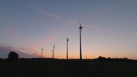 Vista-Aérea-Del-Establecimiento-De-Turbinas-Eólicas-Que-Generan-Energía-Renovable-En-Un-Parque-Eólico,-Noche-Después-De-La-Hora-Dorada-Del-Atardecer,-Paisaje-Rural,-Siluetas-De-Alto-Contraste,-Disparo-De-Drones-Moviéndose-Hacia-La-Derecha