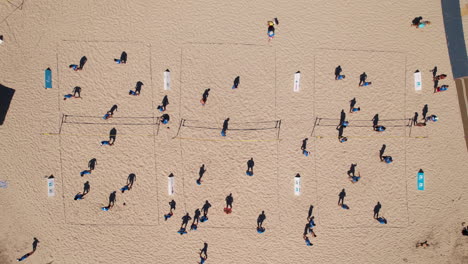 captura aérea de los bañistas involucrados en animados partidos de voleibol.