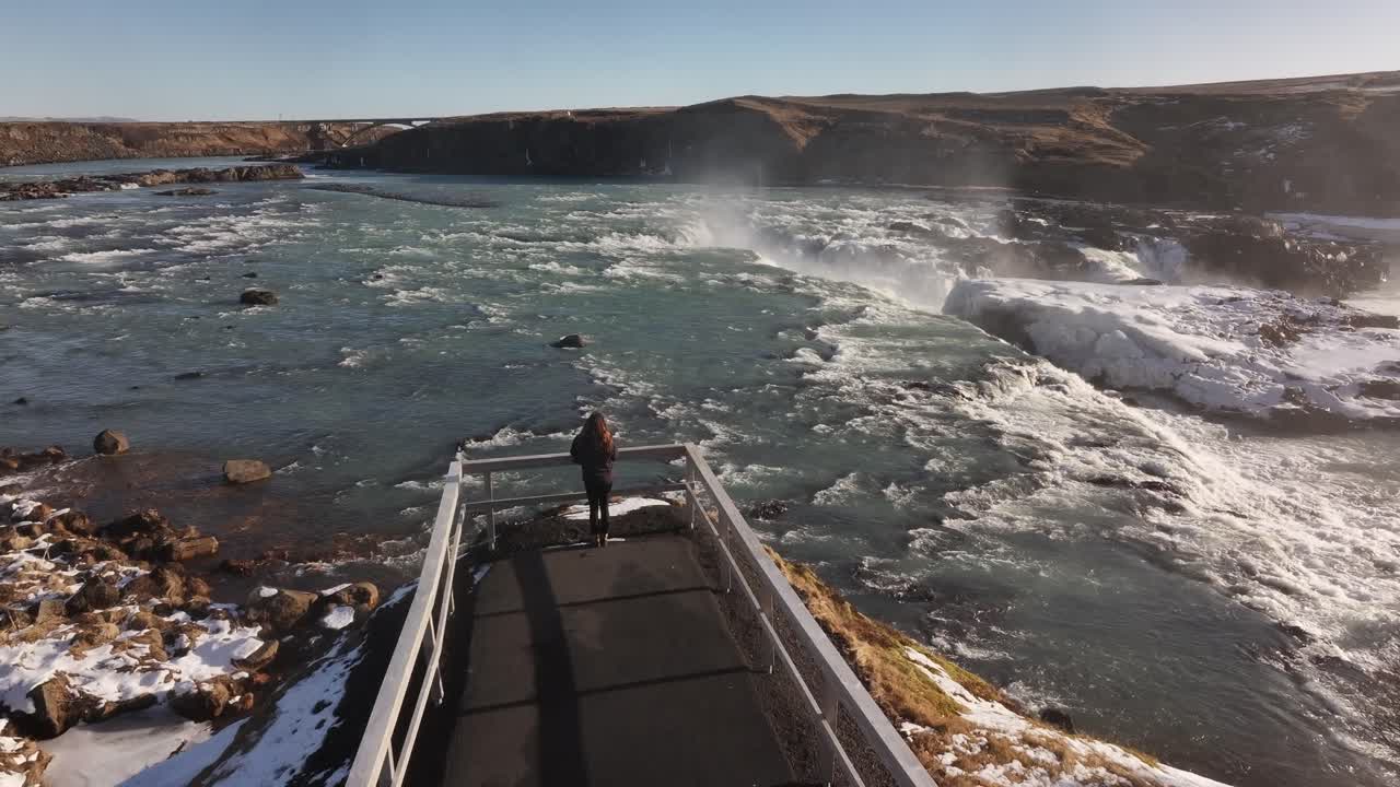 Urriðafoss waterfall with woman on snowy viewpoint deck in south Iceland