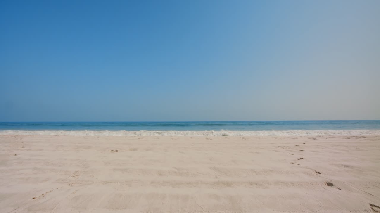 Walking on white sand to a blue calm waves. A blue calm beach waves approaching the camera. 4k footage