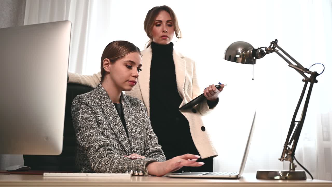 매력적인 젊은 성인 여성들이 사무실에서 모임에서 함께 일합니다. 새로운 직원은 멘토와 상담하고 새로운 프로젝트를 제시합니다. 팀 작업을위한 오픈 스페이스 개념