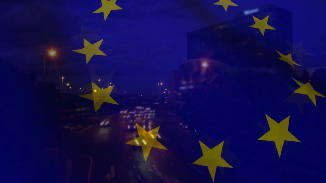 Traffico in partenza, fari che formano striature, motivo con bandiera UE che rimane fisso, scena che mira all'unità