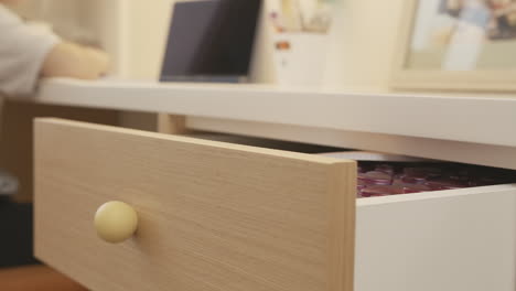 person opening a drawer on a desk