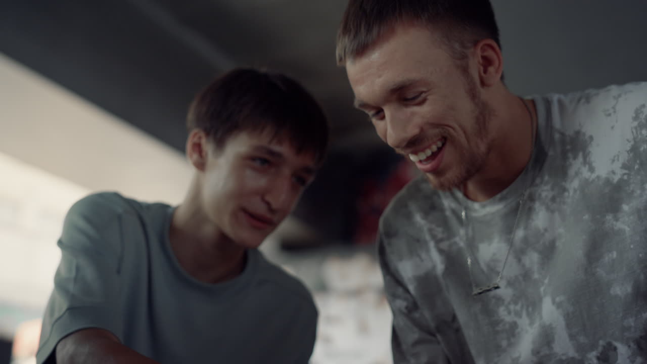 긍정적인 친구들이 스케이트 파크에서 휴대폰으로 소셜 미디어를 즐기고 있습니다.