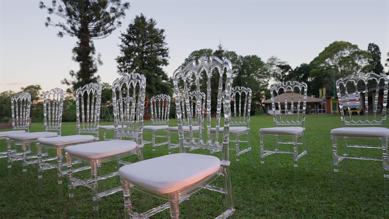 Allestimento per cerimonia nuziale all'aperto con corridoio decorato, composizioni floreali e sedie trasparenti eleganti