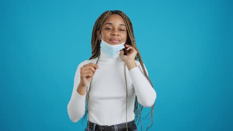 a young black woman puts on a medical face mask for protection