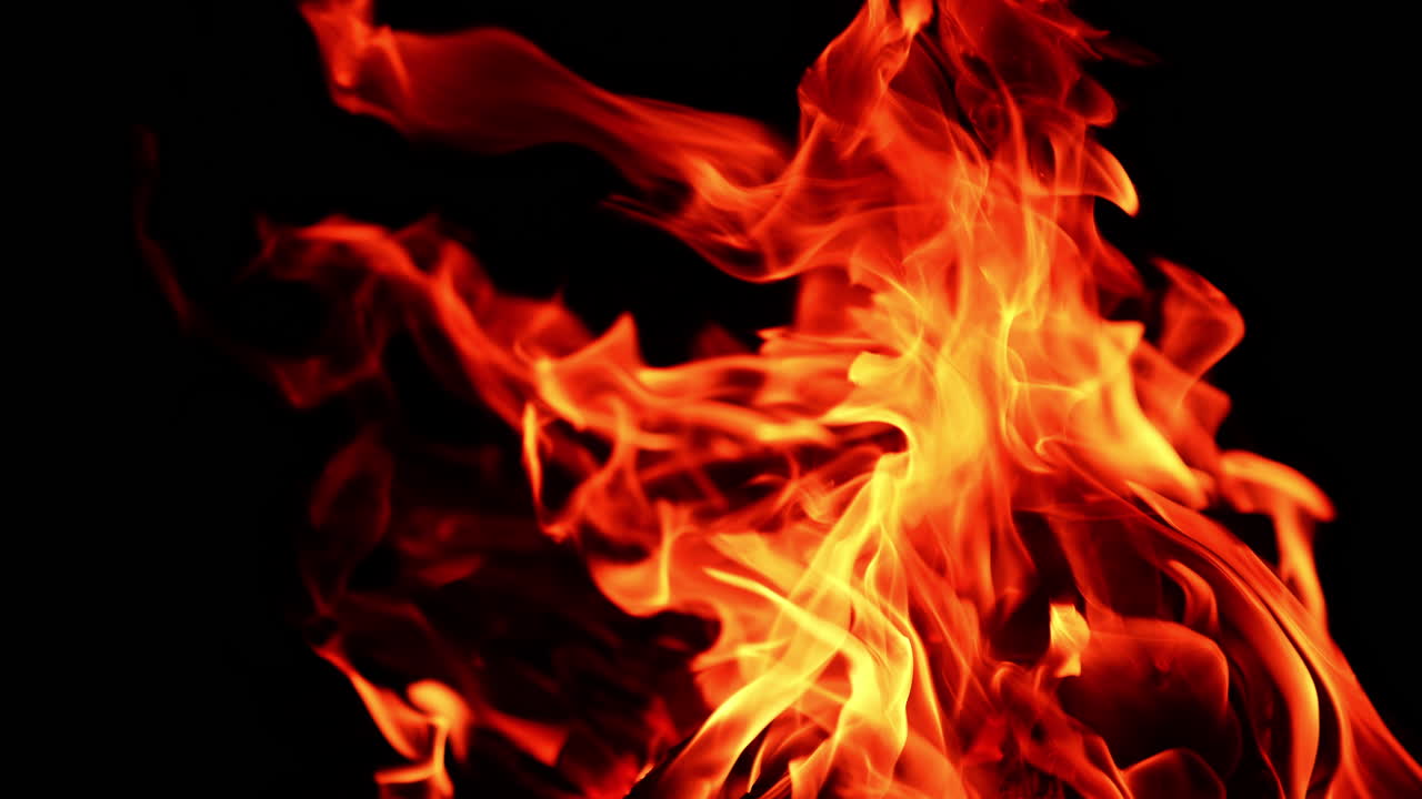 Alcuni bastoncini di legno bruciano nel falò di notte. Fiamme rosse e roventi si innalzano nell'aria. Primo piano.