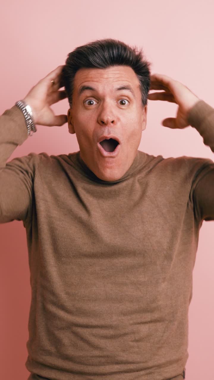 Man Reacts with Shock and Amazement on Pink Background