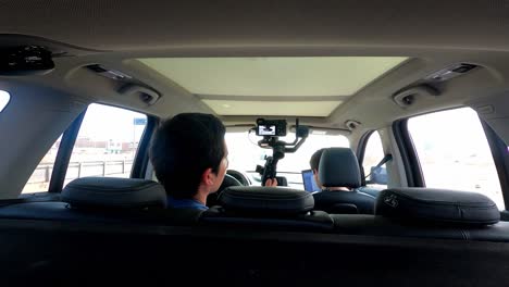 view inside a car from behind of a man filming his friends on a road trip in 4k