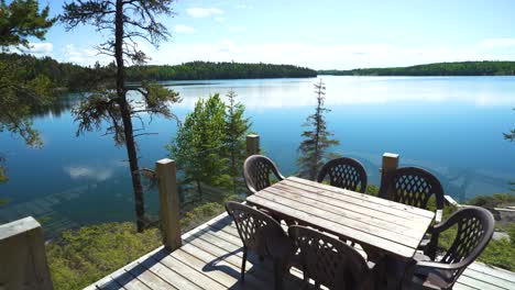 Stepping-out-onto-the-deck-of-a-lake-front-cabin-in-the-sunny,-warm,-summer-weather