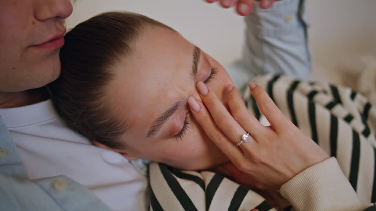 Sad wife watching melodrama with tears on eyes leaning husband shoulder closeup