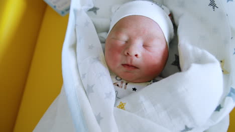 cute newborn baby sleeping covered in blankets. lovely child is winking from the light. close up.