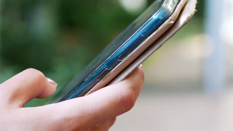 a woman is sitting in a cafe with a smartphone in her hands with a green screen mockup. the girl browses the internet, watches content, videos, blogs.